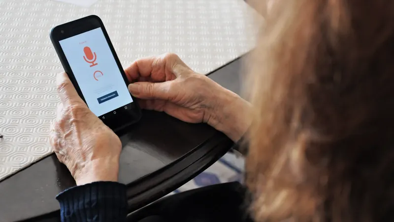 An older woman holding a phone that is recording with HealthTalks, during a usability test